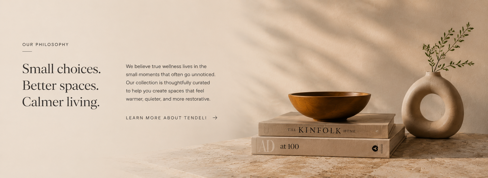 Decorative setup with books, a bowl, and a vase on a wooden surface with a neutral background.